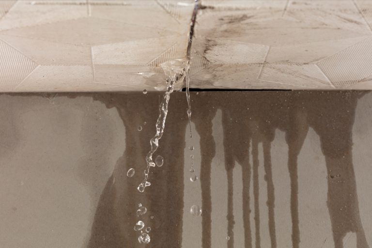 Image of water pouring out of a crack in the ceiling and down the wall.