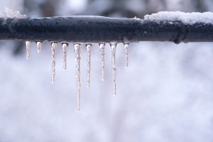 Photo of a pipe, frozen solid with icicles hanging from it.